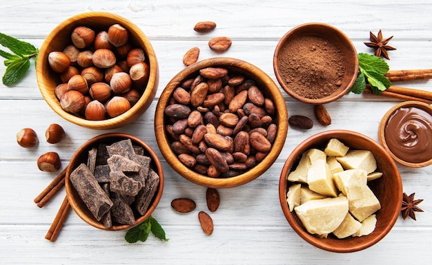 Natural cocoa powder butter chocolate and cocoa beans on a white wooden background