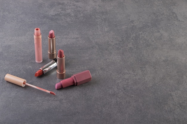 Natural color lipstick in gold packaging placed on a stone table.