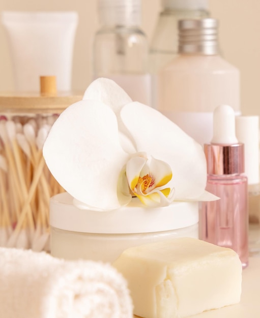 Natural cosmetic jars and skin care accesories with white orchid flower on beige close up