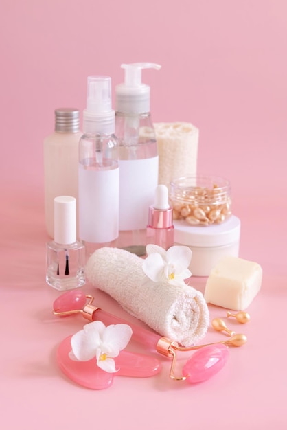 Natural cosmetic jars and skin care accesories with white orchid flower on pink close up copy space