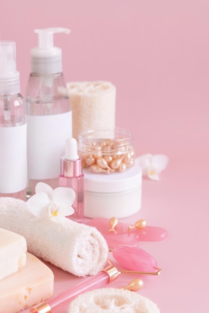 Natural cosmetic jars and skin care accesories with white orchid flower on pink close up copy space