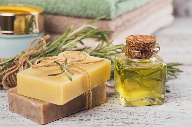 Natural cosmetic oil and natural handmade soap with rosemary on rustic wooden background. Healthy skin care. SPA concept.