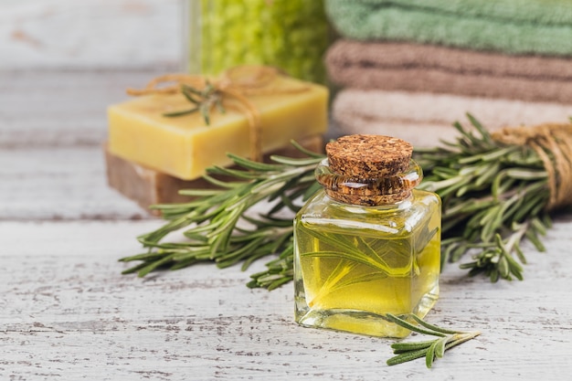 Natural cosmetic oil and natural handmade soap with rosemary on rustic wooden background. Healthy skin care. SPA concept.