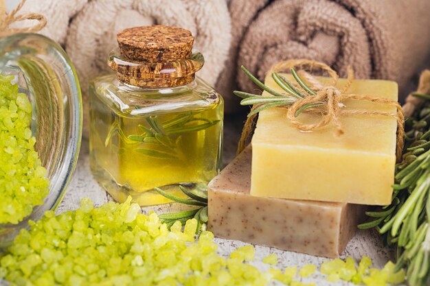 Natural cosmetic oil and natural handmade soap with rosemary on rustic wooden background. Healthy skin care. SPA concept.