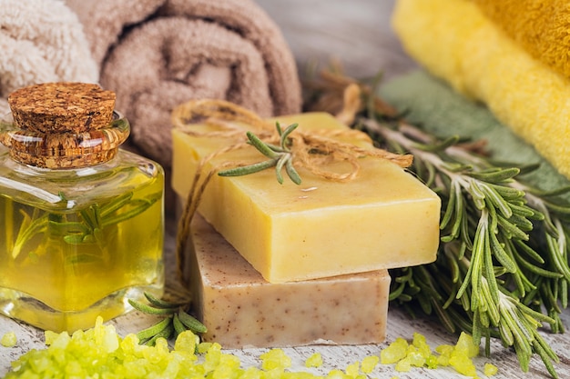 Natural cosmetic oil and natural handmade soap with rosemary on rustic wooden background. Healthy skin care. SPA concept.