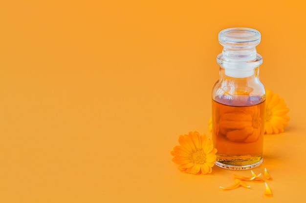 Natural cosmetic oil, a tincture or infusion with Calendula flowers on orange