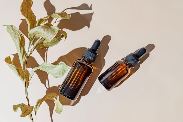 Natural cosmetics in glass bottles with a dropper on a beige background with dry branches The concept of natural cosmetics natural essential oil