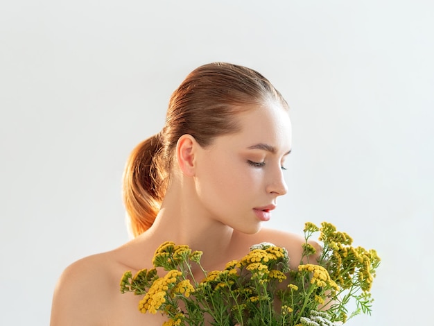 Natural cosmetology Skincare treatment Portrait of woman with nude makeup bare shoulders wild flowers isolated on light white copy space background Homeopathy aromatherapy Freshness detox