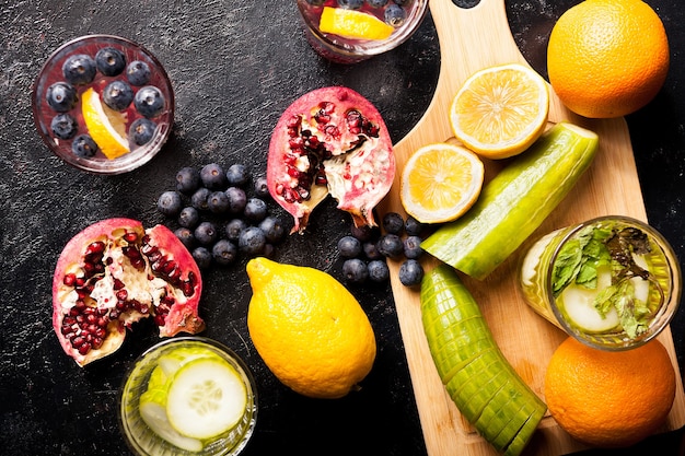 Natural detox water made from infusing berried, fruits and vegetables on dark wooden background