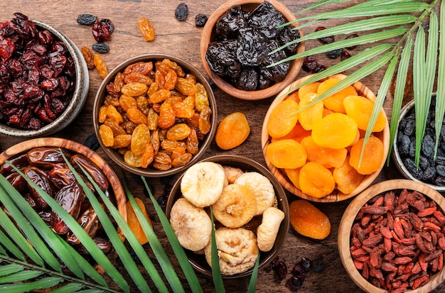 Natural Dried fruits in bowls Healthy food snack sun dried organic mix of apricots figs raisins dates and other on wooden table top view