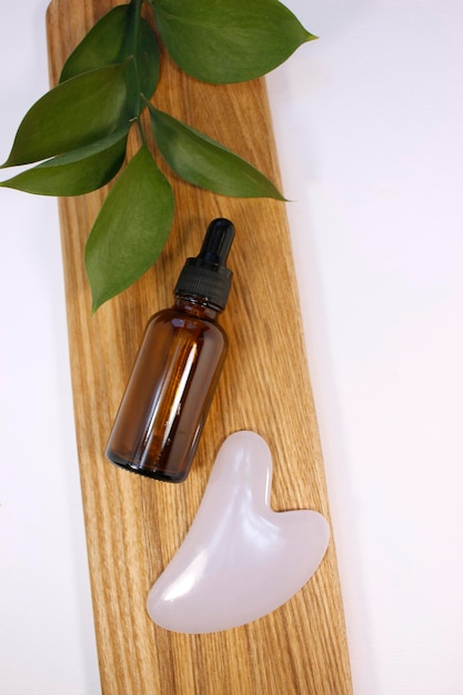 Natural essential oil or serum in brown glass bottle on a wooden podium. Alternative medicine, beauty skin care product. Copy space. Neutral background