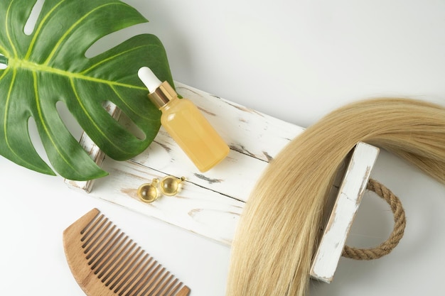 A natural essential oil or serum for hair care in golden capsules lying on a white table Hair care and smoothing concept