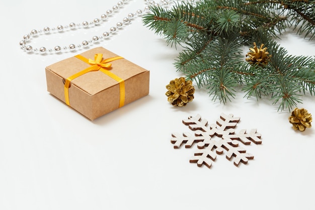 Natural fir tree branch with cones, a gift box and other Christmas ornament on the white background