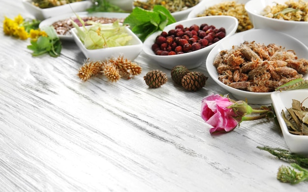 Natural flower and herb selection in ceramic bowls on wooden background