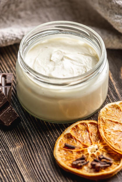 Natural fragrant cream or butter for body in a clear glass jar on a wooden background Concept of organic cosmetics and skin care