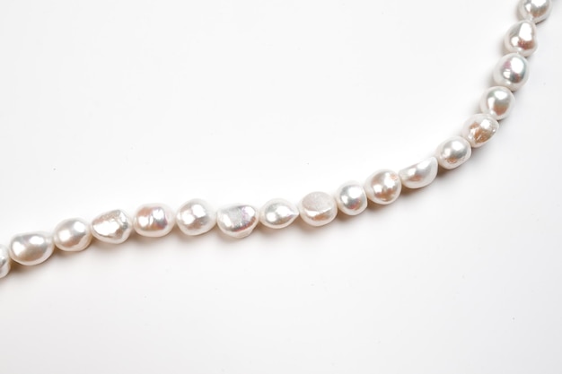 Natural freshwater round pearl beads on white background String of pearls top view