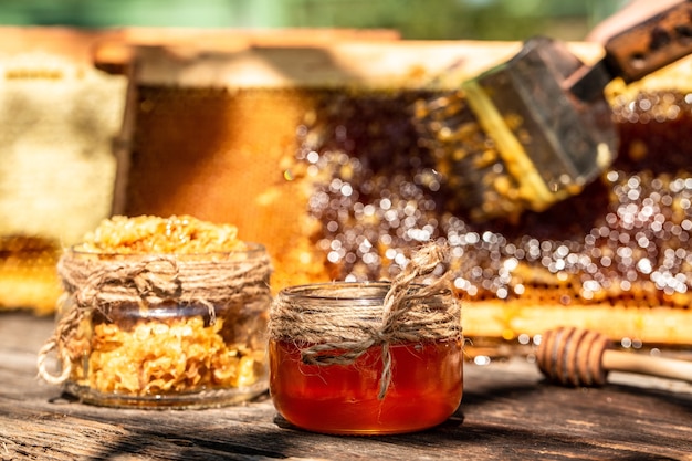 Natural honey comb and a glass jar on wooden table