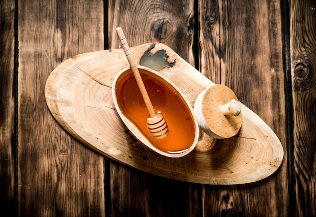 Natural honey in wooden barrel with spoon on wooden background