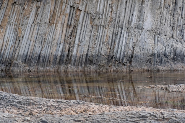 Natural landscape with columnar basalt coastal rock reflected in the water