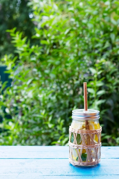 Natural lemonade in a glass jar with paper drinking straw on blue wooden table