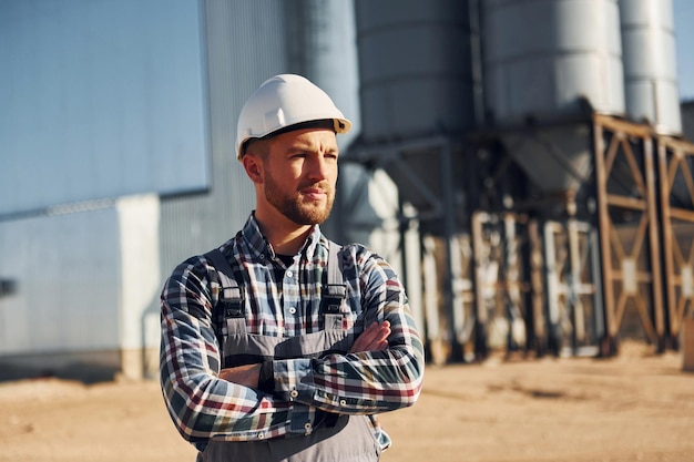 Natural lighting Construction worker in uniform is outdoors near the factory