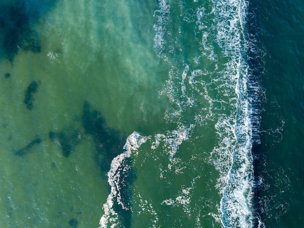 Natural marine seascape with turquoise deep clear water and foam waves. Aerial view from drone. Aqua background with place for text.