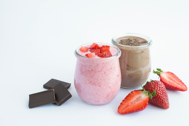 Natural milk yogurt with strawberry and chocolate in the glass jar on the white background Copy space