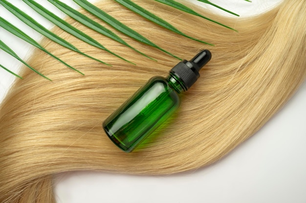 A natural oil or serum for hair care lying on a ply of blonde hair