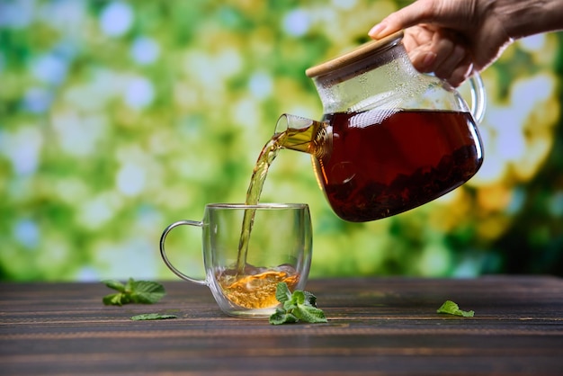 Natural organic herbal tea pours in a glass from glass teapot