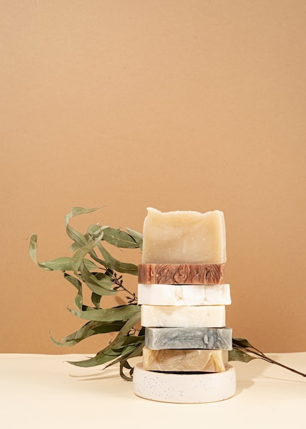 Natural organic selfcare products. Tower stack of different handmade soaps and leaves on cream background. Spa accessories creative art composition on beige background