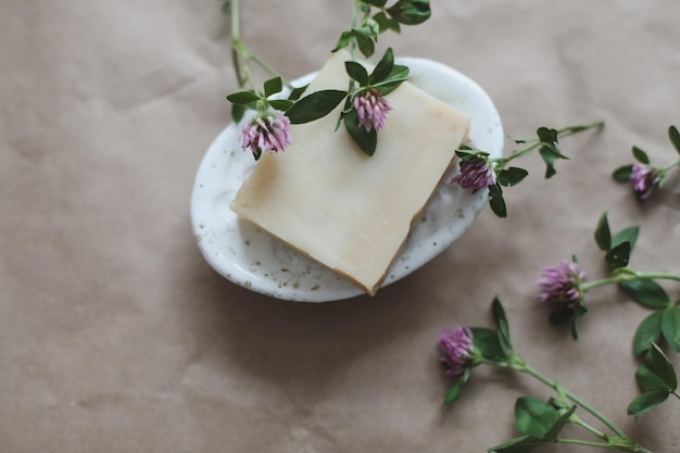 Natural organic soap with flowers and pink towel on craft paper background top view with copyspace