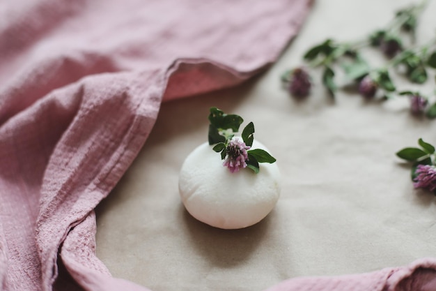 Natural organic soap with flowers and pink towel on craft paper background top view with copyspace