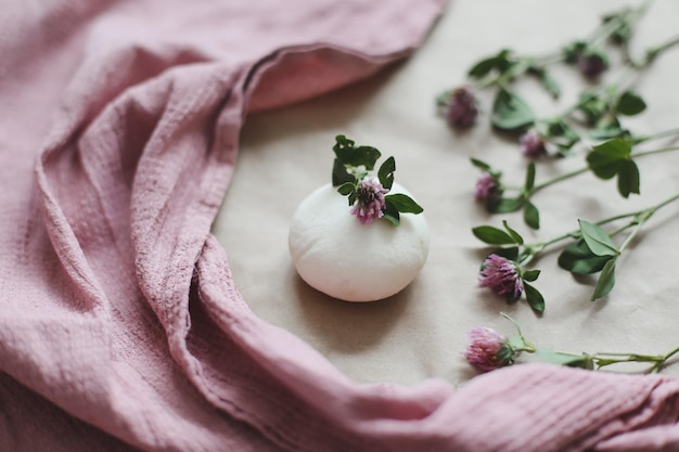 Natural organic soap with flowers and pink towel on craft paper background top view with copyspace