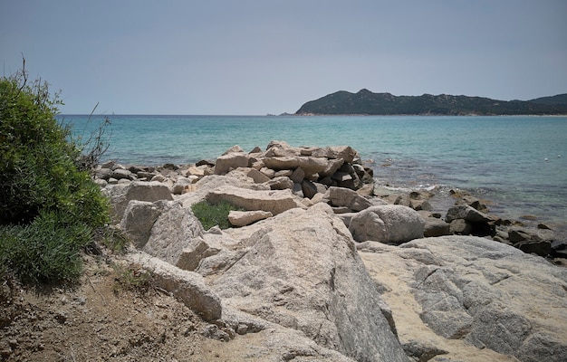 Natural rocks with Mediterranean vegetation overlooking the blue sea in Sardinia.