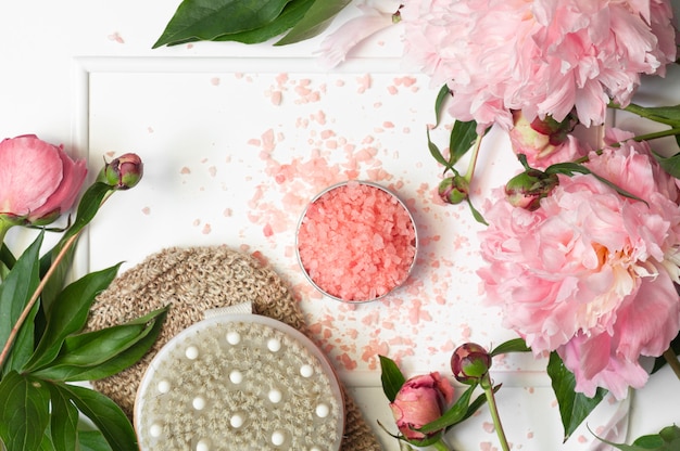 Natural salt for bath with dry massage brush and peony flowers