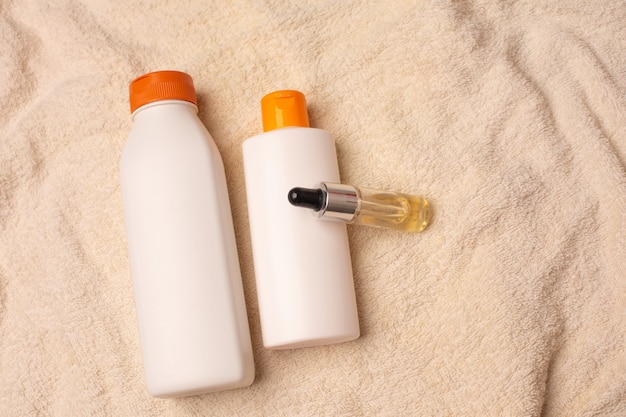 Natural shampoo, hair mask and serum lying on a bath towel in a bathroom. Copy space