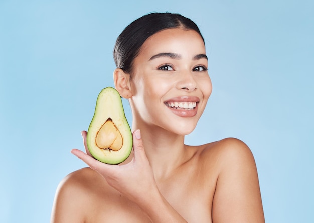 Natural skincare product woman healthcare wellness lifestyle and fresh green avocado fruit Happy face of young girl smile food nutrition and healthy eating diet portrait on blue background