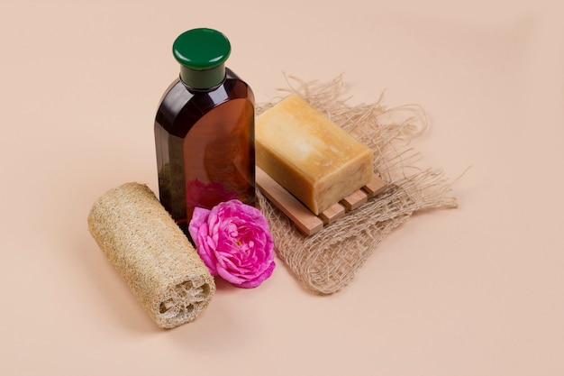 Natural soap loofah  and a bottle of cosmetic product on a beige background