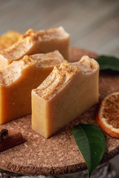 Natural soap and slices of oranges cinnamon and green leaves on the wooden table Concept of eco cosmetics and interesting useful hobby