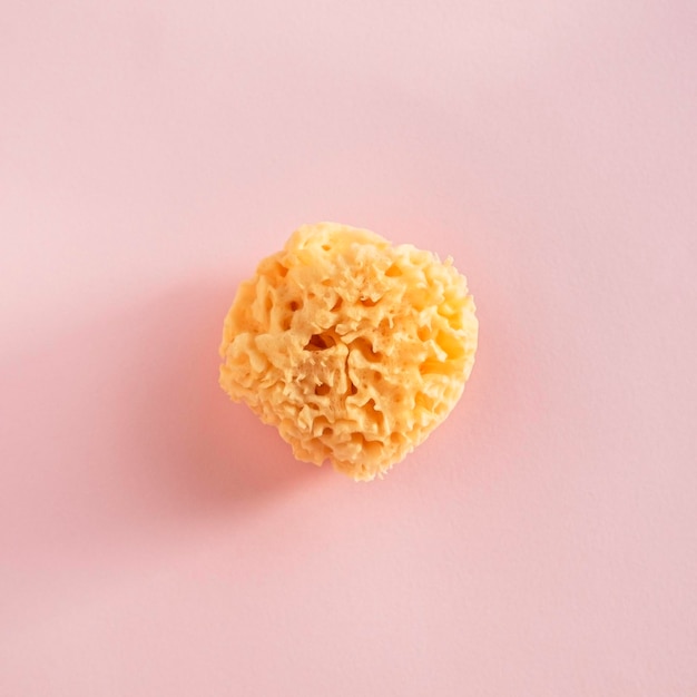 natural sponge for face cleansing on a pink background top view