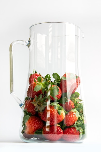 Natural strawberries in a jug closeup with sun glare