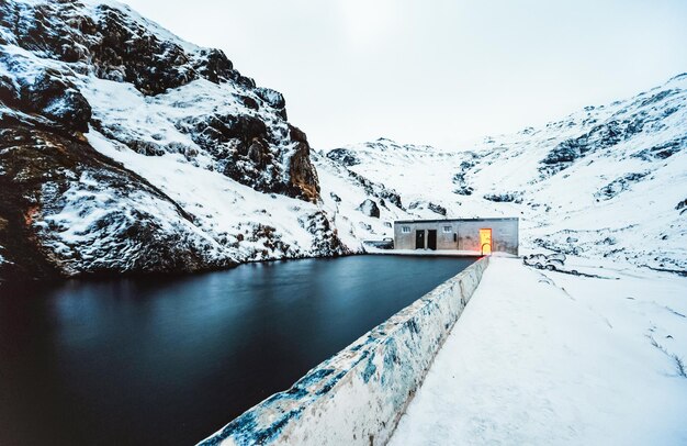 Natural swimming pool Seljavallalaug in iceland with man in water and snowy weather and mountains all around Night photo