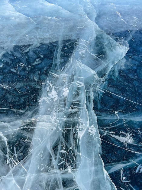 The natural texture of winter ice with white bubbles and cracks on a frozen lake Abstract background of ice and cracks on the surface of frozen Lake Baikal