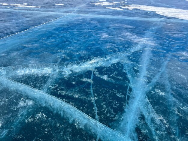 The natural texture of winter ice with white bubbles and cracks on a frozen lake Abstract background of ice and cracks on the surface of frozen Lake Baikal