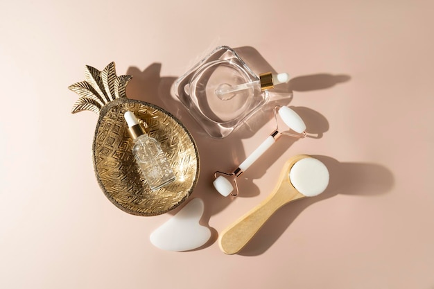 A natural transparent hyaluronic face serum brush and face roller and massager lying on a beige background