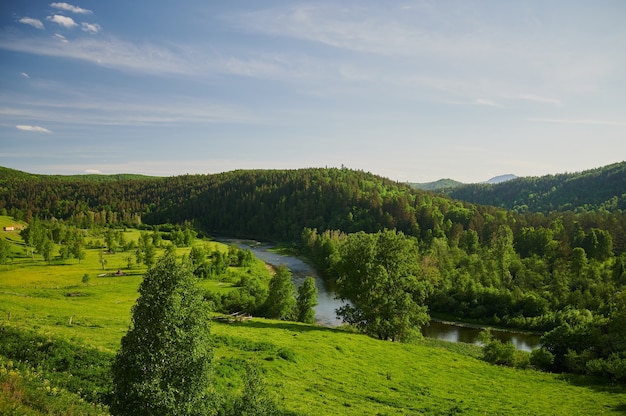 Natural view of green fields in the foreground and mountains of cliffs and hills.