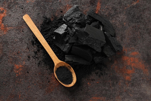 Natural wood charcoal and spoon on textured background