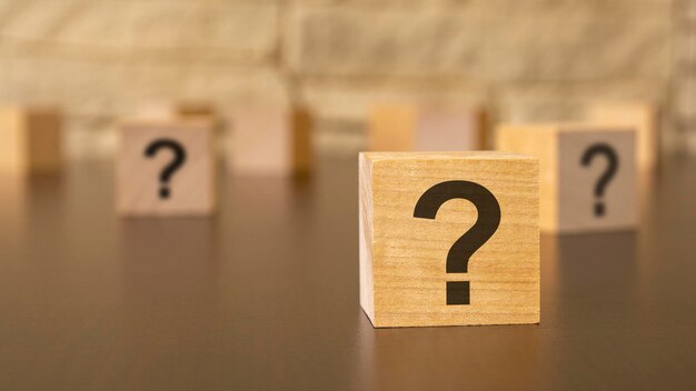 Natural wooden cube with question marks black background