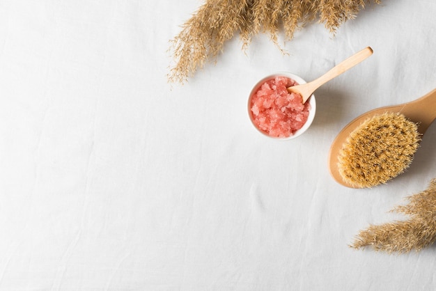 Nature cosmetic scrub and brush with dry grass or flower on white texture background