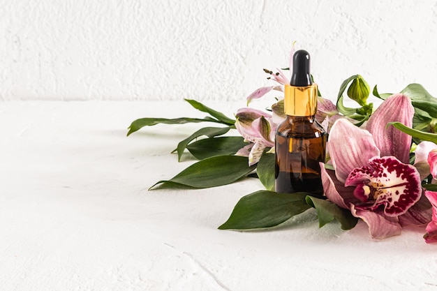 Nature cosmetics in a glass bottle with a pipette and spring flowers on a light background front view space for text